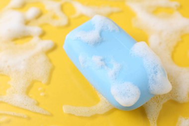 Sarı arka planda köpüklü sabun çubuğu, üst tarafta. Metin için boşluk