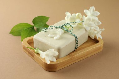 Açık kahverengi arka planda sabun ve yasemin çiçekleri, yakın plan.