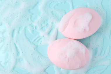 Açık mavi arka planda köpüklü sabun çubukları, düz yatış. Metin için boşluk