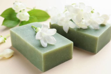 Bej arkaplanda sabun ve yasemin çiçekleri, yakın plan.