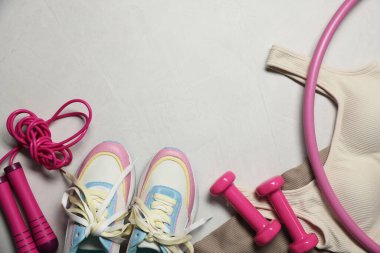 Spor kıyafetleri, spor ayakkabıları, hula hoop, ip atlama ve gri desenli arka planda dambıllar, düz yatış. Metin için boşluk