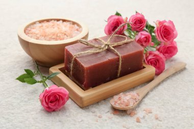 Sabun barı, deniz tuzu ve bej masadaki güzel güller, yakın plan.