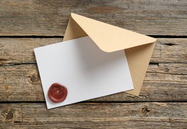 Üzerinde balmumu mühür ve ahşap masa manzaralı boş bir davetiye kartı. Tasarım için boşluk