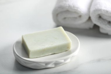 Sabun çubuğu ve havlular beyaz mermer masada, yakın plan.