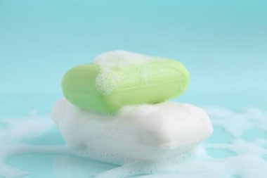 Açık mavi arka planda köpüklü sabun çubukları, yakın plan