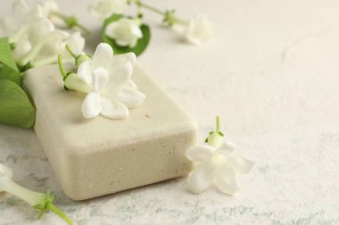 Bir kalıp sabun ve yasemin çiçekleri ışık masasında, yakın plan. Metin için boşluk