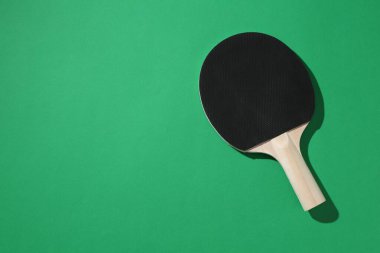 Yeşil arka planda bir pinpon raketi, üst manzara. Metin için boşluk