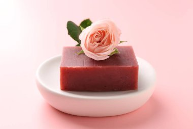 Sabun barı ve pembe arka planda güzel bir gül, yakın plan.