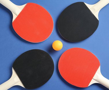 Masa tenisi raketleri ve top mavi arka planda, düz yatıyordu.