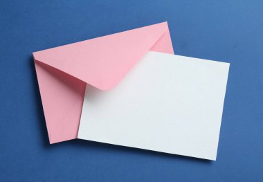 Mavi arka planda boş davetiye ve zarf, üst manzara. Tasarım için boşluk