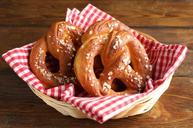 Hasır sepetteki tuzlu krakerler ahşap masada, yakın plan.