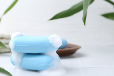 Beyaz masadaki köpüklü sabun çubukları, yakın plan. Metin için boşluk