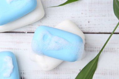 Beyaz ahşap masada köpüklü sabun çubukları, düz uzanmış.