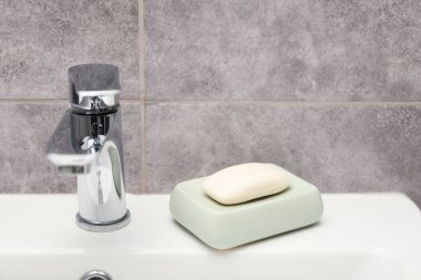 Musluğun yanındaki sabun barı banyoda lavabonun üstünde, yakın plan.