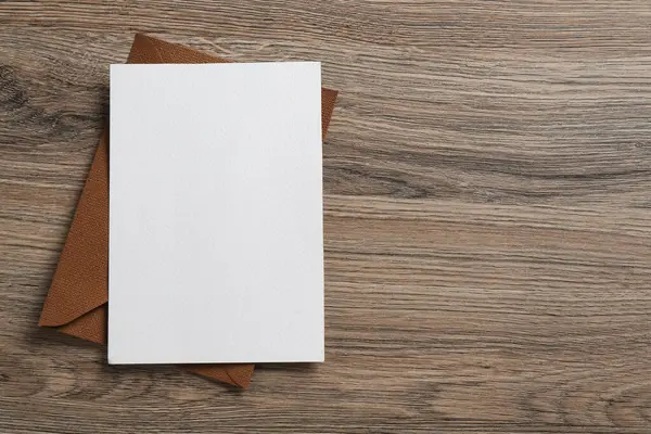 Boş davetiye kartı ve zarf ahşap masanın üstünde, üst tarafta. Tasarım için boşluk