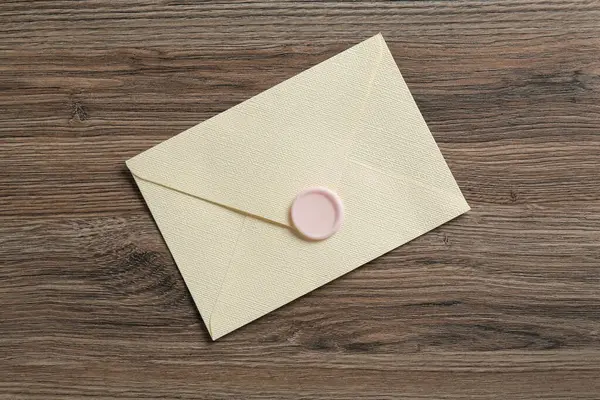Ahşap masa üzerinde balmumu mühürü olan güzel bir davetiye zarfı.