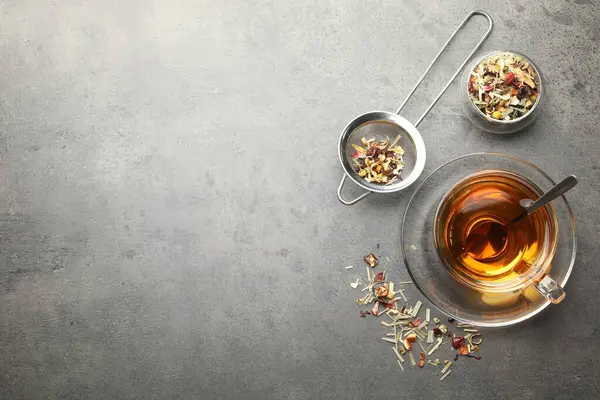 Aromatik bitki çayı ve kuru yapraklar gri masada, düz yerde. Metin için boşluk