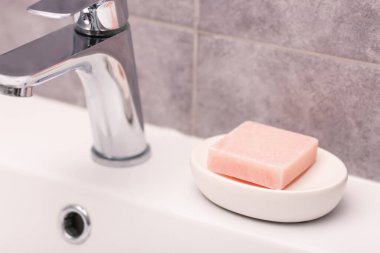 Musluğun yanındaki sabun barı banyoda lavabonun üstünde, yakın plan.