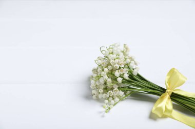 Beyaz ahşap arka planda, vadideki güzel nilüfer çiçekleri buketi, yakın plan. Metin için boşluk