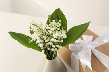 Vadi çiçeklerinin güzel zambakları ve beyaz masada hediye, yakın plan.