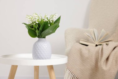 Bir buket güzel vadi zambağı vazoda, kahve masasının üstünde.