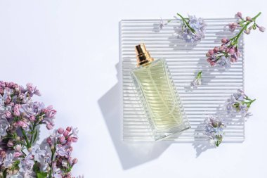 Bir şişe parfüm ve beyaz arka planda güzel leylak çiçekleri.