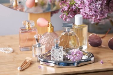 Parfüm şişeleri, aksesuarlar ve ahşap masada leylak çiçekleri.