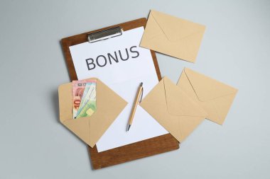 Kelime bonusuyla pano ve açık gri arka planda para zarfları, düz yatıyordu