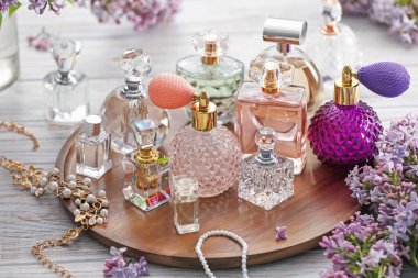 Beyaz ahşap masada parfüm, aksesuar ve leylak çiçekleri.