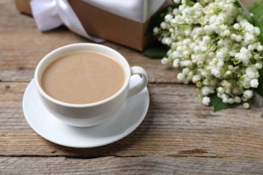 Bir buket güzel vadi zambağı çiçeği, ahşap arka planda kahve ve hediye, yakın plan.