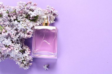 İçinde parfüm ve mor arka planda leylak çiçekleri olan bir şişe. Metin için boşluk