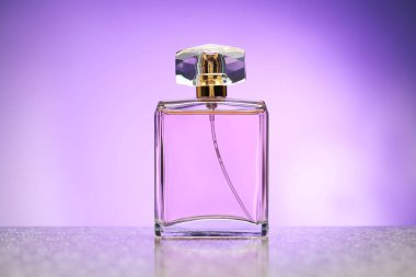 Ayna yüzeyinde menekşe eğimli arka plana karşı bir şişe parfüm