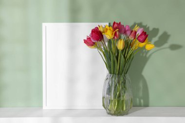 Güzel lale buketi ve çerçeve renkli duvarın yanındaki masada.