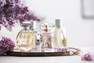 Beyaz ahşap masada parfüm şişeleri ve leylak çiçekleri.