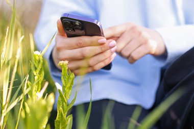 Açık havada akıllı telefondan bitki tanıma uygulaması kullanan bir kadın.