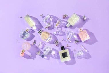 Düz kompozisyon, parfüm şişeleri ve mor arka planda leylak çiçekleri vardı.