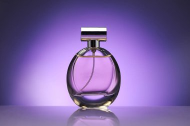 Ayna yüzeyinde mor renge karşı bir şişe parfüm.