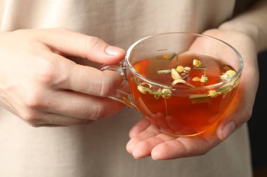 Cam bardakta aromalı bitkisel çayı olan kadın, yakın plan.