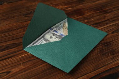 Para bonusu. Tahta masanın üzerinde dolar banknotu olan zarf, yakın plan.
