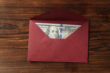 Para bonusu. Tahta masanın üstünde dolar banknotuyla zarf, üst manzara.