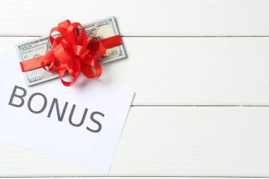 Para bonusu. Beyaz ahşap masa üzerinde fiyonklu ve kartlı banknotlar, düz yatıyordu. Metin için boşluk