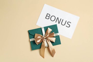 Zarfta altın fiyonk ve kart var. Bej arka planda bonus var.