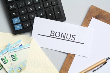 Açık gri zemin üzerinde kelime bonusu, para, pano ve hesap makinesi olan kart, düz yatıyordu