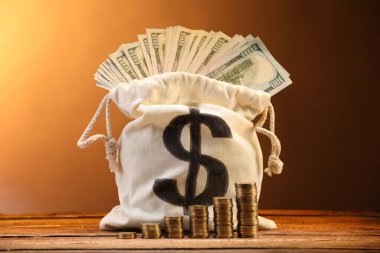 Dolar banknotları ve kahverengi gradyan karşı ahşap tablo üzerine istiflenmiş bozuk paralar ile çanta