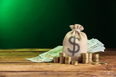 Çanta, dolar banknotları ve ahşap masaya istiflenmiş paralar yeşil eğimli arkaplan, metin için boşluk