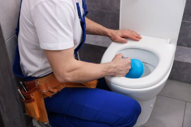 Tesisatçı tuvalet tıkanıklığını açıyor, içeride pompa var, yakın plan.