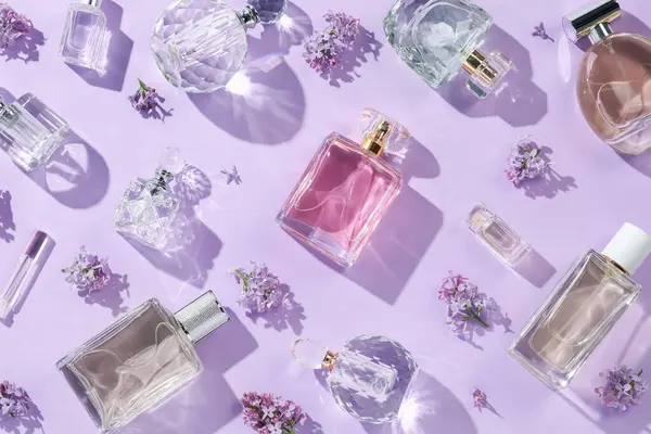 Lüks parfümler ve açık mor arka planda güzel leylak çiçekleri.