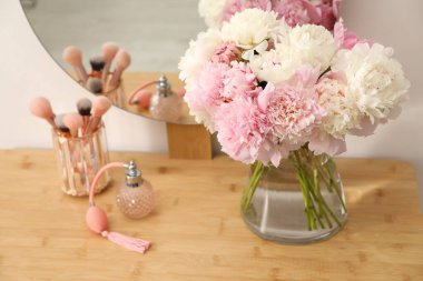 Vazodaki güzel şakayıklar, parfümler, fırçalar ve kapalı alandaki ahşap kibir aynaları.