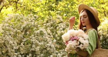 Parkta şakayık demeti olan güzel bir kadın. Kamera sağa hareket ediyor