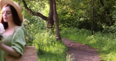 Parkta şakayık demeti olan güzel bir kadın. Kamera sola hareket ediyor